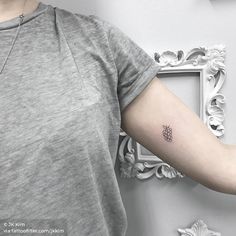 a person with a small pineapple tattoo on their left arm, next to a white frame