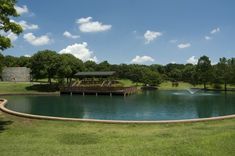 a large pond in the middle of a park with a gazebo and water fountain