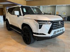 a white suv is parked in a showroom