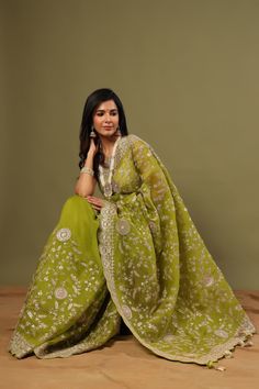 Look royal in this olive green organza saree with embroidery on festive occasions! It comes with a matching blouse piece. Disclaimer: The actual product may vary slightly from the image. These are custom orders, hence expect slight variation in color, placement of the motif or buta. ESTIMATED DELIVERYBecause this is a custom order, it would take about 4 weeks from the date of purchase. RETURN POLICYThis product is a custom order and cannot be returned or exchanged. Embroidered Green Pre-draped Saree In Dola Silk, Embroidered Green Organza Pre-draped Saree, Green Organza Saree Traditional Wear, Green Organza Saree With Zari Work, Designer Green Organza Saree, Green Chikankari Embroidery Pre-draped Saree For Diwali, Green Chikankari Embroidered Pre-draped Saree For Diwali, Green Pre-draped Saree With Chikankari For Diwali, Green Chikankari Pre-draped Saree For Diwali