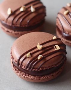 three cookies with chocolate frosting and nuts on top