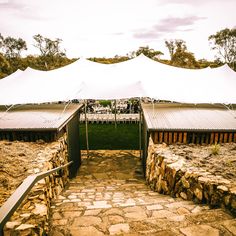 an outdoor wedding venue with white tents and stone steps leading up to the reception area