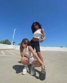 two women in white shirts and black shorts posing for the camera