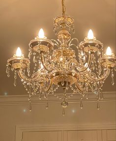 a chandelier hanging from the ceiling in a room with white walls and doors