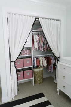 an open closet with white curtains and pink baskets