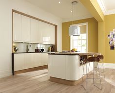 a kitchen with yellow walls and white cabinets is pictured in this image, there are two bar stools at the center of the island