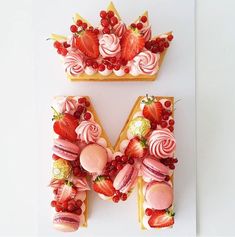 the letter m is made out of cake and fruit on it's sides,