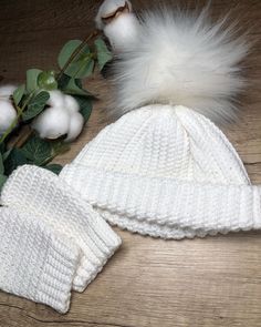 two white knitted hats next to cotton flowers