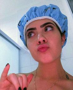 a woman wearing a blue scrub hat and holding her finger up