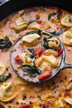 a ladle full of tortellini shells and spinach in a white sauce