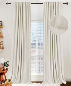 a room with white curtains and a hat on the window sill