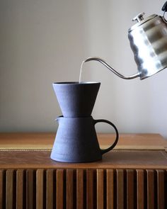 a coffee pot is pouring water into a cup