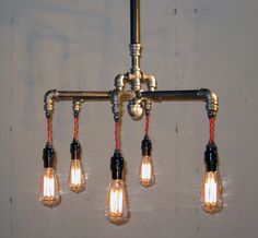 five light bulbs hanging from an industrial style chandelier with pipes and fittings