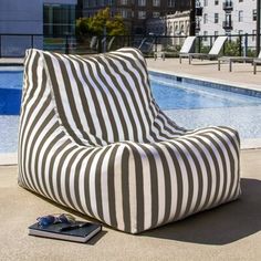 a green and white striped bean bag chair next to a swimming pool