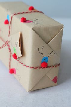 an origami envelope decorated with red and blue pom - poms is tied up