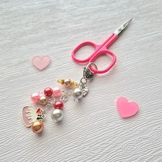 a pair of pink scissors sitting on top of a table next to hearts and other items