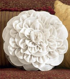 a white flower pillow sitting on top of a couch