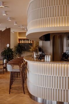 the interior of a restaurant with tables, chairs and plants on the bar counter area