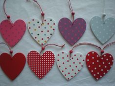 six heart shaped ornaments hanging from strings on a white tablecloth with polka dot designs