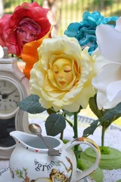 there are four different colored flowers in the vases on the table with an old clock