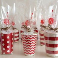 four red and white cups with candy canes in them on a table next to each other