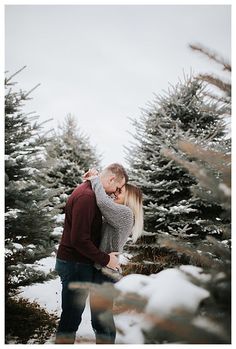 a man and woman standing next to each other in front of some snow covered trees