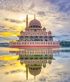 a large building sitting on top of a lake next to a sky filled with clouds