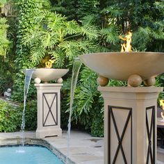 an outdoor fountain in the shape of a bowl with water running out of it, next to a swimming pool surrounded by greenery