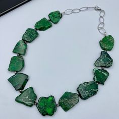 Delve into a world of natural elegance with our Deep Green Jasper Nuggets Necklace. This statement piece combines the organic allure of earth with sophisticated style, creating an accessory that's both visually stunning and meaningful. The necklace measures approximately 23 inches in length, making it a versatile piece to accentuate any outfit. This one-of-a-kind artisan necklace made from dyed natural imperial jasper beads different shapes 20~62 x 15~50 x 4~7 mm. - silver plated finding - clasp is stainless steel lobster claw - stainless steel textured chain This Deep Green Jasper Nuggets Necklace is versatile enough to dress up your casual ensemble for a day out, or to add a touch of earthy elegance to your evening wear. Its soothing shades of green will bring a pop of color to any look, Green Jasper Jewelry With Natural Stones, Green Jasper Jewelry With Gemstone Beads, Green Tumbled Natural Stone Jewelry, Artisan Green Stone Necklaces, Nature-inspired Jasper Necklaces With Natural Stones, Nature-inspired Jasper Stone Necklaces, Artisan Green Stone Necklace, Elegant Jasper Beaded Necklaces With Natural Stones, Green Natural Stones Nature-inspired Necklace