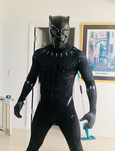 a man in a black panther costume standing on a hard wood floor