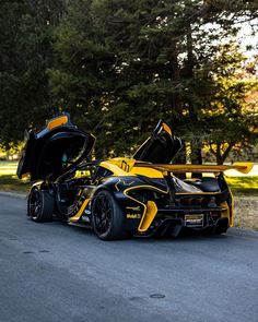 a yellow and black sports car parked on the side of the road with its doors open