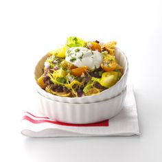 a white bowl filled with salad on top of a red and white napkin