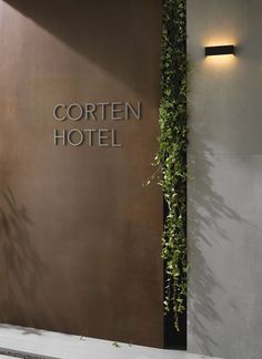 the corner of a hotel lobby with plants growing on the wall and sign that reads, corten hotel