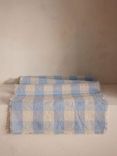 a blue and white checkered blanket laying on top of a floor next to a wall