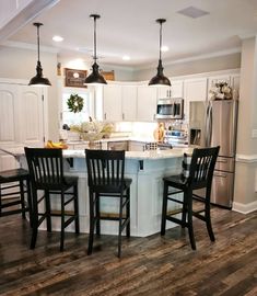 a kitchen with an island and four chairs around it in front of the counter top