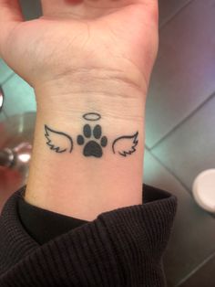 A tattoo with wings a paw print and a halo Tattoos For Women Dog, Tattoo With Dog Paw Prints, Small Black Panther Tattoo, Tattoos Dog Paw, Dog Paws Tattoo Ideas, Tattoo Ideas Paw Print, Tattoo For Lost Dog, Infinity Dog Tattoo