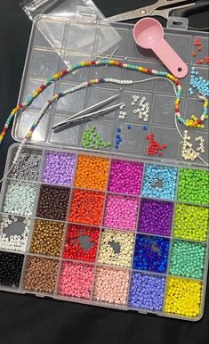 beads, scissors and other crafting supplies are on a black table with plastic bags