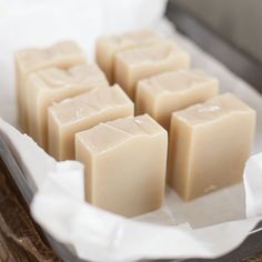 four bars of soap sitting on top of a white tray next to some tissue paper