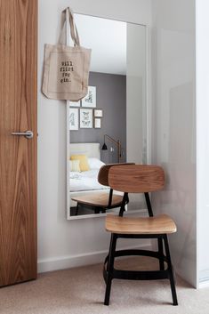 a wooden chair sitting in front of a mirror next to a white wall and door