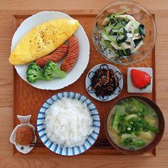 a wooden tray topped with plates and bowls filled with food