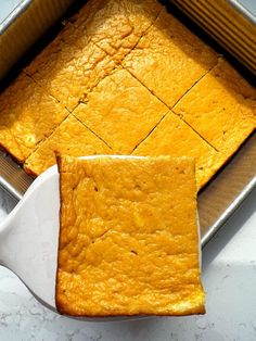 a pan filled with yellow cake next to a spatula on top of a counter