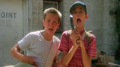 two young boys standing next to each other with their mouths open and one holding a cell phone