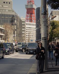 a woman standing next to a pole on a city street