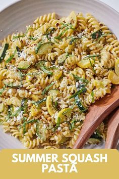 a white plate topped with pasta and veggies next to a wooden serving spoon