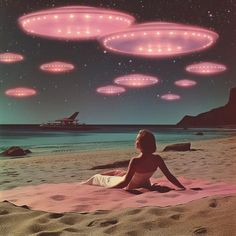 a woman sitting on top of a sandy beach under flying pink circles in the sky