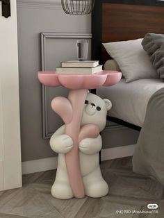 a pink and white table with a teddy bear holding a book on it's leg