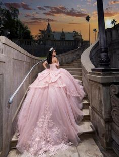 a woman in a pink dress sitting on some stairs