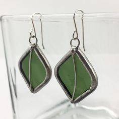 "Opaque, olive green stained glass earring pair edged in silver, accented with silver wire. The simple French hook ear wires are sterling silver.  Total Size: 1 15/16\" x 7/8\" each Each item by Faerie Glass is 100% uniquely hand-crafted with quality materials that are lead-free. NOTE - All photographs are taken in effort to best represent the product. Color of actual jewelry may vary slightly from photographs." Nickel-free Silver Earrings With Recycled Glass, Nickel-free Silver Earrings In Recycled Glass, Stained Glass Earrings, Goth Earrings, Stained Glass Jewelry, Nugget Necklace, Olive Leaf, Glass Rings, Stained Glass Mosaic