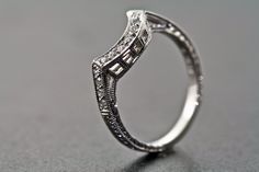 a close up view of a diamond ring on a gray surface with an intricate design