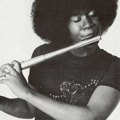 a woman with an afro holding a flute in her hands